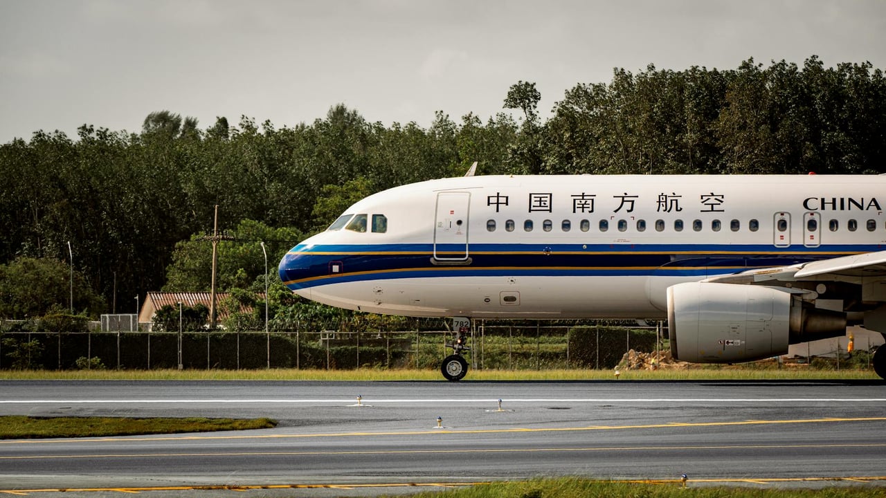 China Southern Airlines airplane on runway with green backdrop.