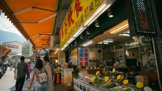 Vibrant Asian street market scene with various food stalls and a crowd of people exploring.