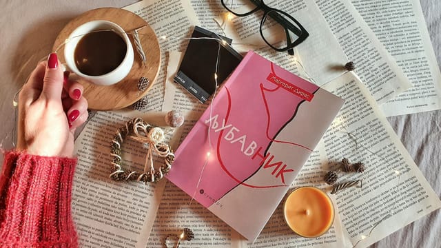 A cozy setup of coffee, book, and string lights for a relaxing reading experience.