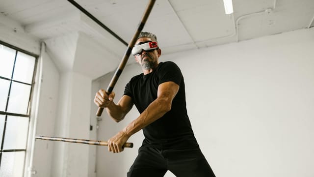 Adult man practicing martial arts with VR headset in modern studio.