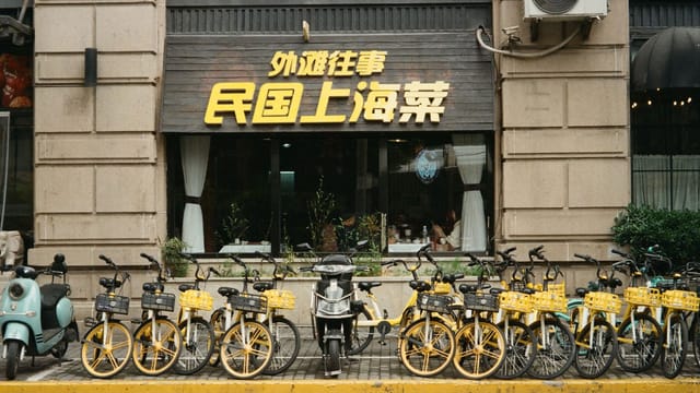 Bicycle and scooters parked outside a restaurant in vibrant Shanghai, China.