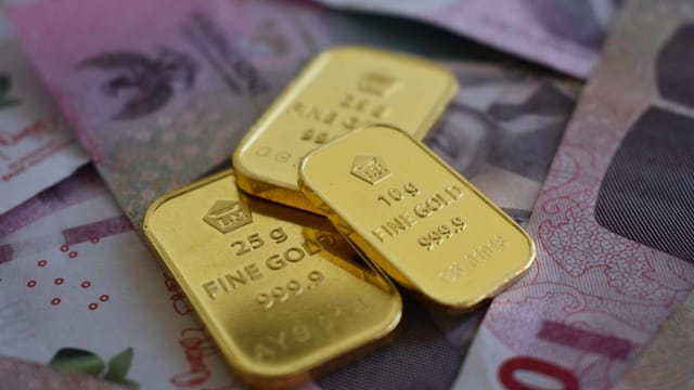 Detailed gold bars layered over Indonesian currency, highlighting wealth and investment.