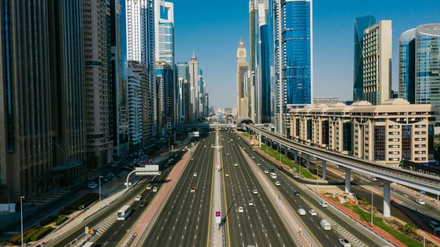 A breathtaking aerial view of Dubai's busy highway flanked by iconic skyscrapers on a clear day.