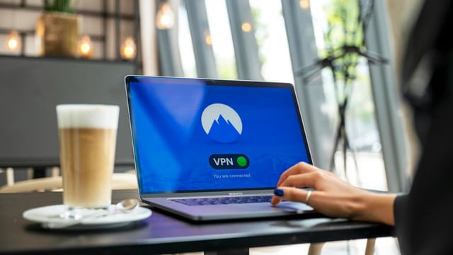 A person using a laptop with a VPN connection in a modern cafe setting, showcasing remote work and internet security.