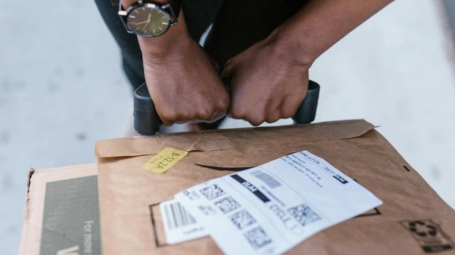 Close-up of delivery worker handling a package with care outdoors.