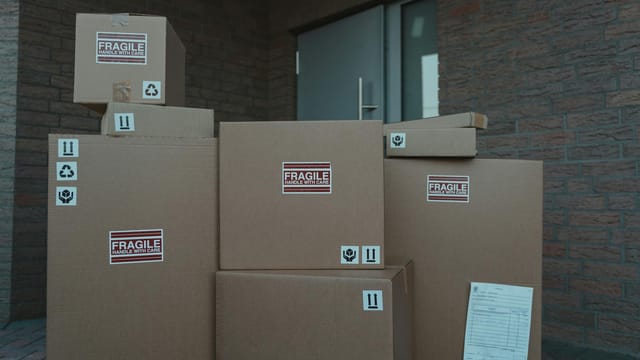 Several cardboard packages marked as fragile stacked at a building entrance.