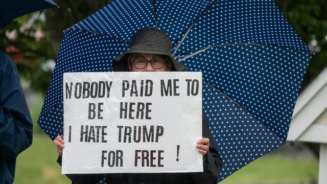 Protester with sign and umbrella during a rally in Rhode Island.