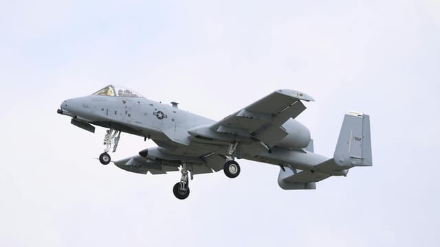 A military A-10 Thunderbolt II aircraft flying in a clear sky, showcasing its powerful design.