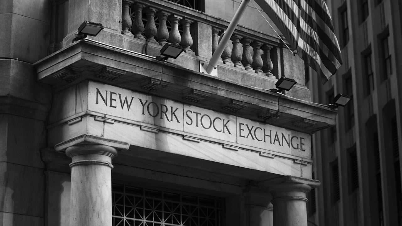 Black and white photo of the New York Stock Exchange facade with USA flag.