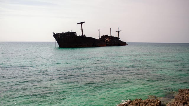 Rusty shipwreck in clear turquoise waters off Kish Island, Iran.