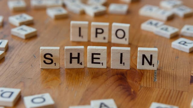 Creative representation of Shein's IPO using letter tiles on a wooden surface.