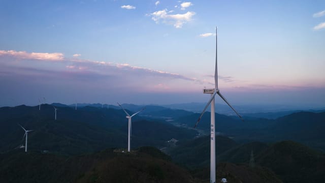 Aerial view of wind turbines in a scenic mountainous landscape in Jiujiang, China, at sunset.