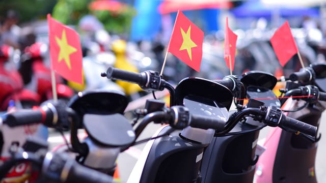 Row of scooters adorned with Vietnamese flags, showcasing a vibrant street scene.