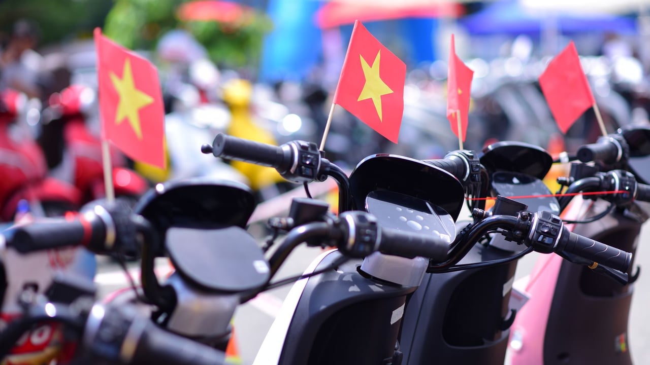 Row of scooters adorned with Vietnamese flags, showcasing a vibrant street scene.