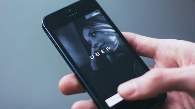 Close-up of a hand holding a smartphone with the Uber app open on the screen.