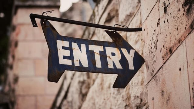 An old metal ENTRY sign with arrow on a stone wall in Jerusalem, Israel.