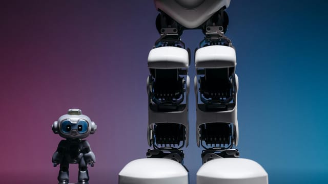 A large robot stands beside a small toy robot with colorful studio lighting, showcasing technology innovation.