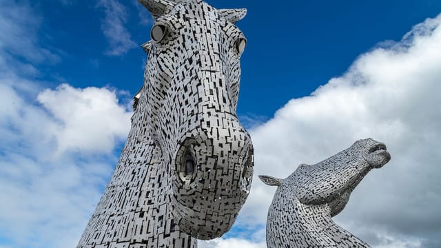Stunning close-up of The Kelpies sculptures in Grangemouth, Scotland, under a bright blue sky.