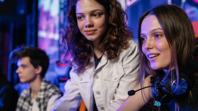 Three teenagers enjoying an immersive gaming session in a lively e-sports venue.