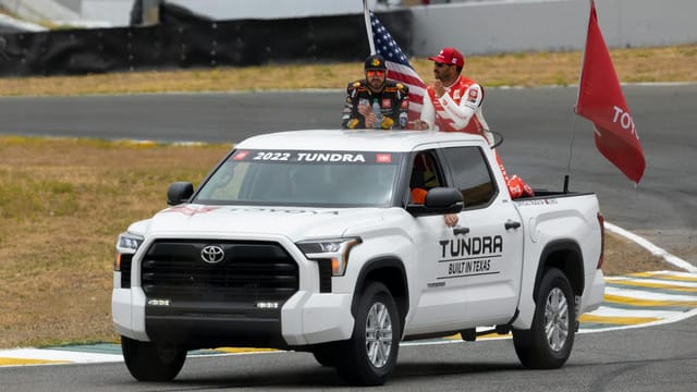 A Toyota Tundra showcasing at a racing event with drivers and flags. Perfect for motorsport enthusiasts.