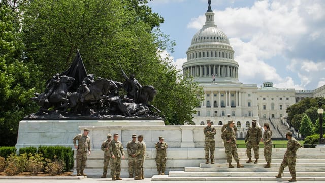 Soldiers stand in front of the US Capitol and statue, highlighting protection and symbolism.