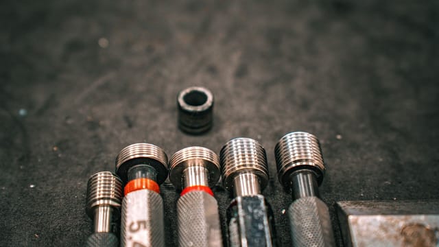 Detailed macro shot of metal industrial tools aligned on a gritty surface.