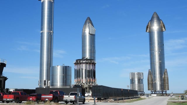 Starship prototypes standing tall at Brownsville, Texas launch site under clear skies.
