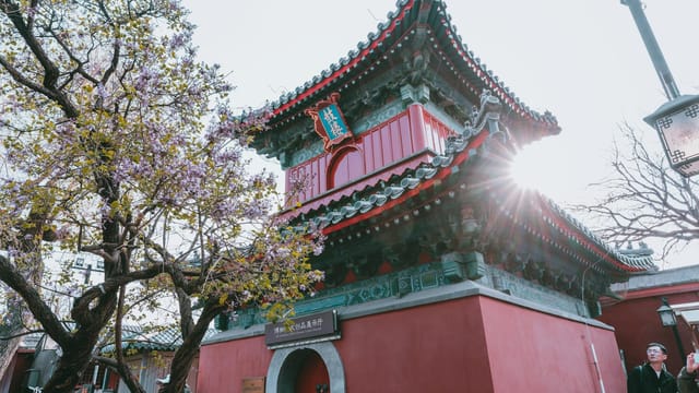 A vibrant traditional pagoda in a sunlit park in Beijing, China.