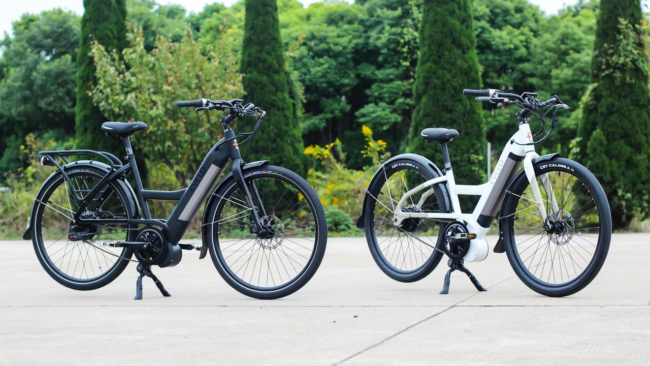 Two electric bicycles parked outdoors in a scenic summer setting.