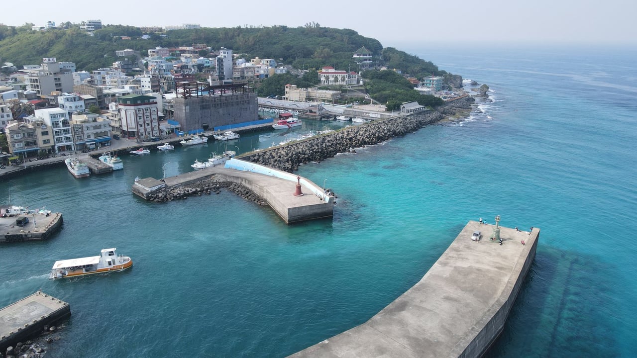 Stunning aerial view of a coastal town with a vibrant harbor and clear blue waters.