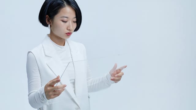 Young woman interacting with a futuristic transparent screen, showcasing modern technology concepts.