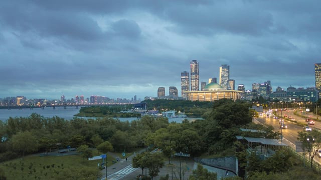 Dynamic view of Seoul's skyline featuring iconic structures and Han River at dusk.