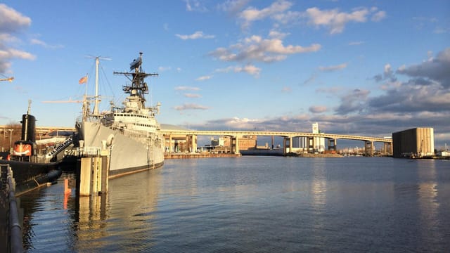 USS Little Rock docked at Buffalo waterfront, with city bridge skyline and serene waters.