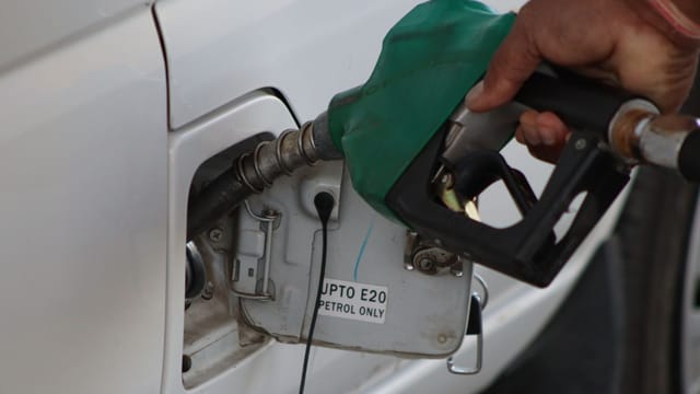 Close-up of a hand refueling a vehicle. E20 petrol pump nozzle in use.