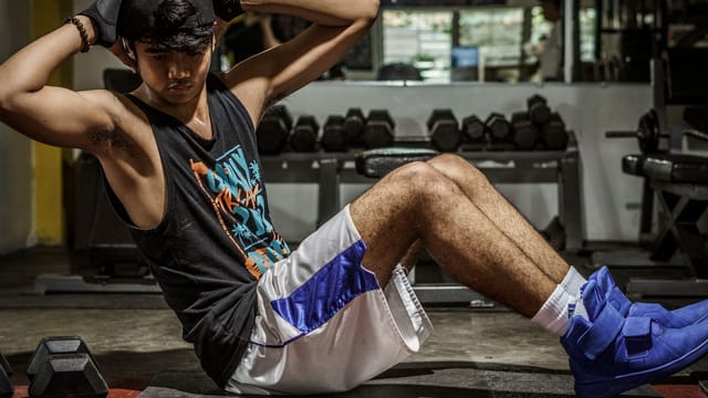 A young man performing sit-ups in a Manila gym, showcasing strength and fitness.