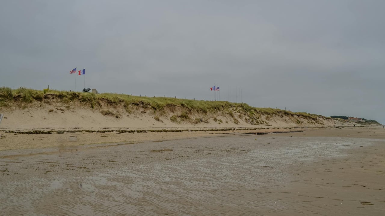 A historic view of Utah Beach in Normandy, France, with American and French flags symbolizing liberation.