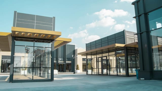 Empty modern urban space with glass facades under a clear sky.