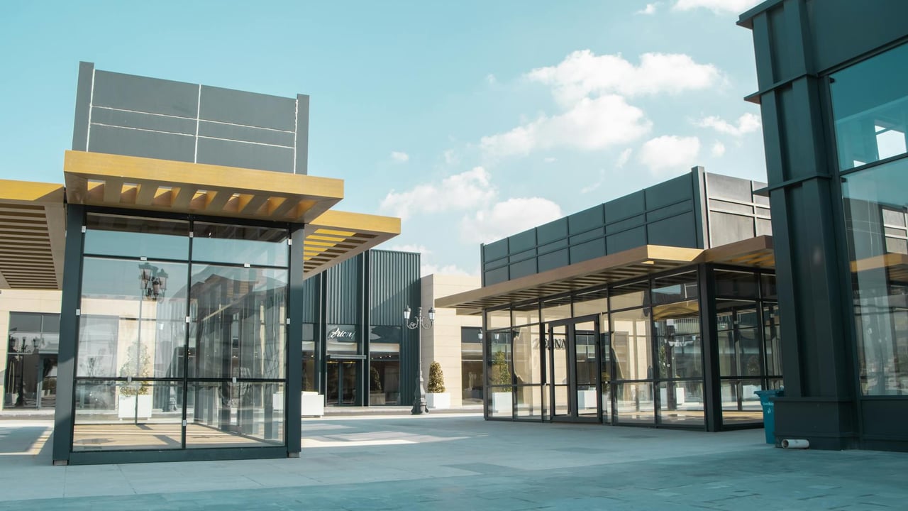 Empty modern urban space with glass facades under a clear sky.