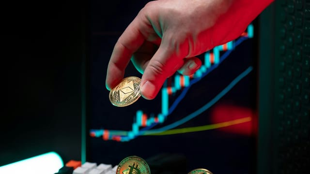 A hand holding cryptocurrency coins with a financial chart in the background, depicting market trends.