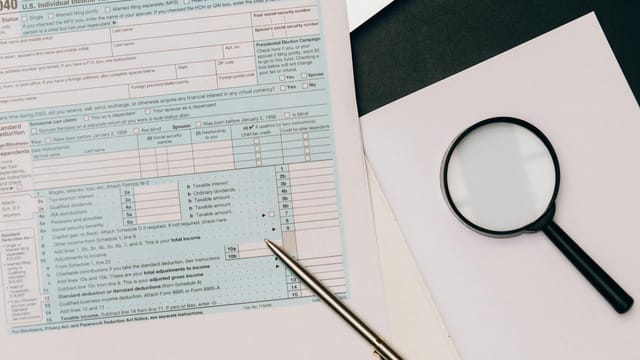 A detailed view of a tax return form with a pen and magnifying glass, perfect for financial themes.