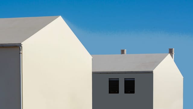 Contemporary minimalist architecture with white houses contrasting a vivid blue sky.