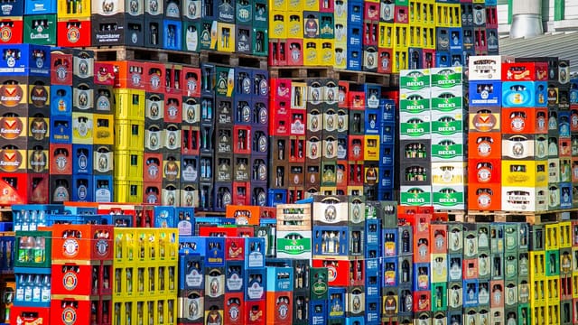 A vibrant display of beer crates stacked in a warehouse, showcasing various brands.