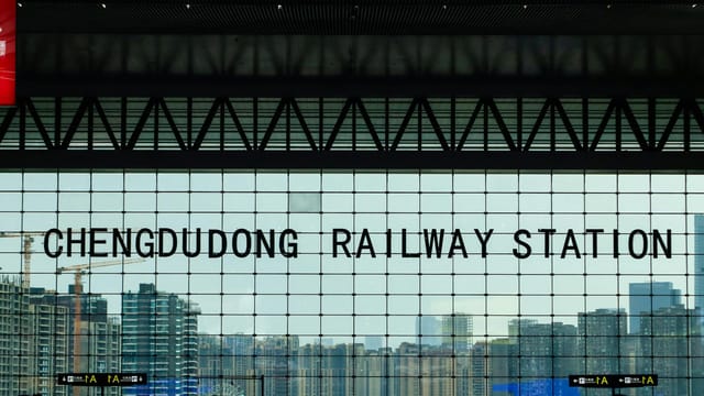 A view from inside Chengdu East Railway Station showcasing the city skyline through large glass windows.