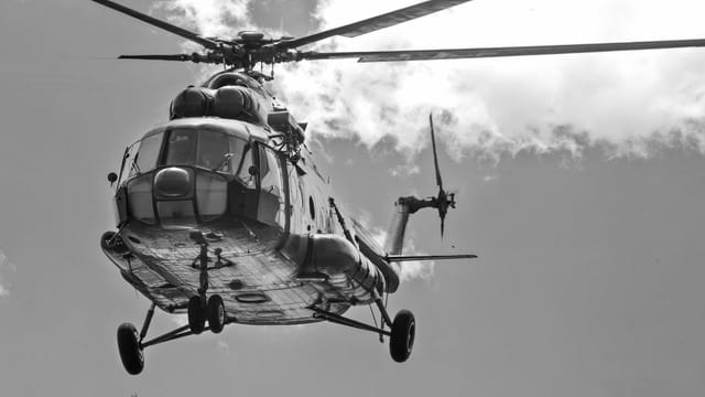 A striking black and white image of a helicopter flying against a cloudy sky in Jashore, Bangladesh.
