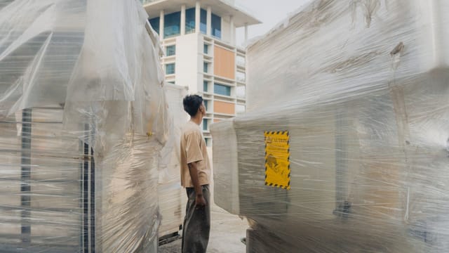 A worker stands between wrapped machinery on a construction site in Dhaka, Bangladesh.