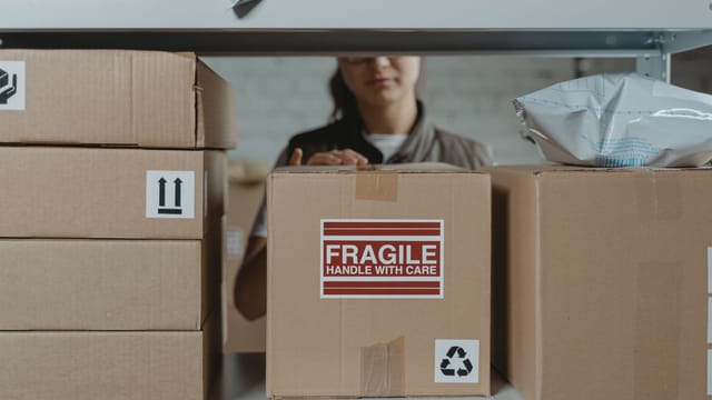 Illustrative image: A person organizing fragile cardboard boxes in a warehouse setting.