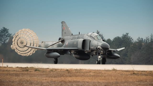 Turkish Air Force jet fighter landing with parachute deployed on runway in Türkiye.
