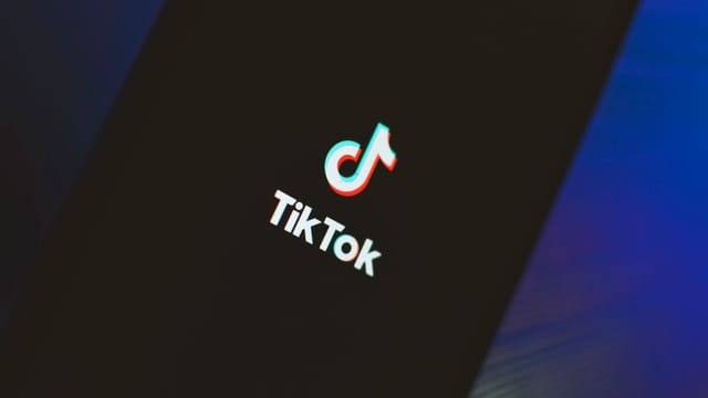 A close-up view of the TikTok app logo illuminated on a smartphone screen.