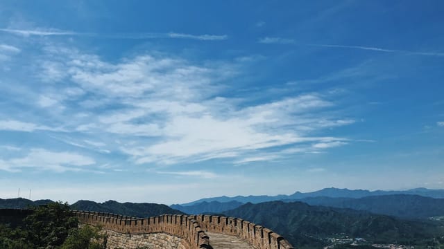 A breathtaking view of the Great Wall of China stretching across lush mountains under a vibrant blue sky.