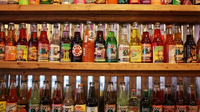 A vibrant collection of vintage soda bottles displayed on wooden shelves in a store.